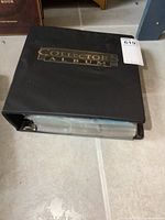 Closed black Collector's Album binder on tile floor