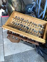 View of vintage collectible spoons mounted on rods inside a Birds Eye maple wood frame, showing multiple spoons with various decorative handles.