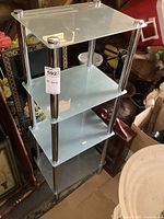 Full view of the four-tier chrome and frosted glass display shelf showing shelves and chrome supports.