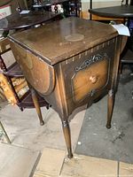 Front three-quarter view of stand with drop leaves down revealing drawer and turned legs