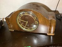 Front view of wooden vintage Mauthe mantle clock showing clock face with gold-tone Arabic numerals and hands under glass cover.
