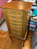 Front view of the wooden jewelry stand showing multiple drawers and metal handles.