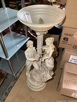 Full view of large resin figural lamp showing wide ribbed shade and sculpted man offering flowers to a woman on base