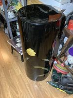 Front and side view of large cylindrical lacquered pedestal with black finish and hand-painted yellow floral decoration.
