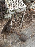 Antique sawmill blade assembly showing a circular 17-inch blade attached to a rusted metal arm with a heavy spiked base for pole mounting, resting on the ground.