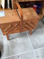 Side view of vintage wooden sewing box closed, showing cantilever style and handle