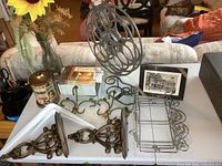 Large vintage 15 inch metal movie reel displayed on table with accompanying metal shelves, ornate metal brackets, glass vase with flowers, wooden condiment set, and metal tin.