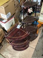 Overview of both wooden corner shelves stacked next to boxes, showing their size difference and condition