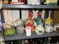 Shelf containing 9 diverse ceramic and porcelain teapots of small to full size with various colors and designs.