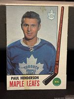 Front of the Paul Henderson hockey card showing the player in a Toronto Maple Leafs jersey with a hockey stick and the Maple Leafs logo.