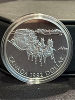 Close-up of the coin reverse showing a stagecoach and horses with inscription 'CANADA 1992 DOLLAR'.