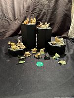 Full view of 21 ceramic animal figurines arranged on black stands and surface, showing variety of species and colors.