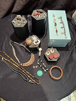 Overview of all jewelry pieces showing rings, necklaces, bracelets, earrings, brooches, and the watch arranged on stands and boxes