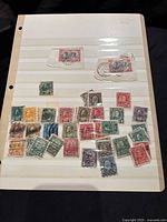 A page of Canadian postage stamps in various colors and denominations, very used with cancellation marks and wear.