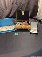 Photo showing jewelry box with assorted bracelets and necklace in blue box and ring in jewelry box.