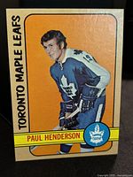 Front of Paul Henderson 1972-73 Topps hockey trading card showing player in Toronto Maple Leafs uniform with orange background.