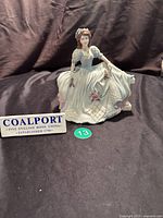 Front view of Coalport Age of Elegance On The Balcony figurine with Coalport sign beside it.