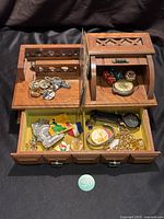 Top compartments of wooden organizer with keys, rings, coins, dice, pocket watch, loupe