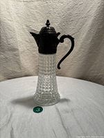 Full side view of the vintage pitcher showing the clear crystal body with geometric block pattern and dark silver plated top, spout, and handle.