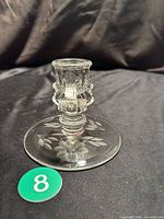 Full view of the clear glass candlestick holder showing the etched flower design on the base and intricate molded candle cup.