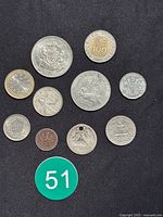 All coins and tokens laid out on a black surface including a hanging eagle coin and various silver and bi-metallic coins.