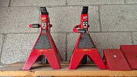 Front view of two red Big Red 2 tonne car jack stands side by side on wooden shelf.