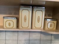 Set of four vintage kitchen tins arranged on a kitchen shelf showing the full set and their embossed labels