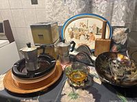 Overview of various vintage kitchenware items showing two stovetop espresso makers, enamel trays, glass bowls, metal tins, and other kitchen accessories.