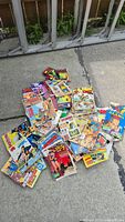Collection of colorful vintage Italian comic books laid on the pavement including titles depicting Western scenes, fantasy, and crime themes.