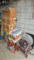 Stack of 9 boxes of glass jars next to large metal cooking pot with lid, propane burners and hoses on the floor.