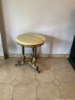 Full view of vintage round side table with cream marble top and ornate brass base, showing overall design and condition.