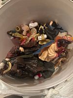 Top-down view showing assorted small figurines piled in a white container.