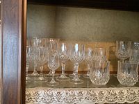 Shelf view with various sizes of vintage cut crystal glasses showing detailed cut patterns and shapes.
