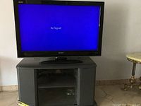 Sharp 45-inch TV on black TV stand. Screen shows a blue "No Signal" display with visible crack.