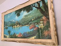 Angled close-up of framed seaside landscape showing vibrant colors and frame texture