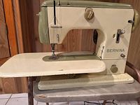Front view of vintage Bernina sewing machine showing cream and olive green colors, folding sewing platform, and needle area.