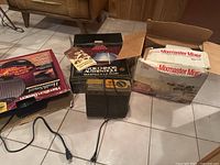 Overview of the assortment of vintage kitchen appliances, showing a Hamilton Beach box, an authentic Chinese wok box with manual, and a Mixmaster Mixer box.