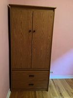 Front view of vintage wooden wardrobe cabinet showing full height and two lower drawers.