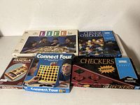 Classic board games lot including The Game of Life, Chinese Checkers, Mancala, Connect Four, and Checkers Special in original boxes stacked and displayed