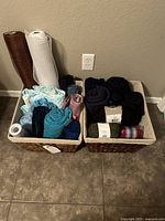 Two woven baskets filled with multiple fabrics and yarn skeins in various colors and textures.