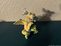 Front and side view of colorful Mood Dragon figurine showing smiling dragon with wings and intricate details.