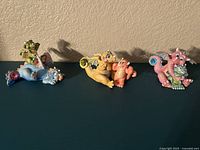 Front view of three mood dragon figurines in blue, yellow and orange, pink and green colors, showing distinct facial expressions and poses.