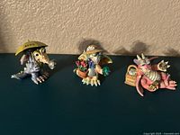 Front view of three mood dragon figurines representing April, May, and June with colorful details and accessories like umbrella, hat, and butterflies