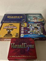 Photo showing the five board game boxes: Sequence, Upwords (unopened), Deer in the Headlights, Mathematics Lab (unopened), and VisualEyes.