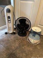 Lot of three home comfort appliances: Holmes radiator heater, Comfort Zone fan, Vicks humidifier on floor near door