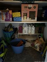 Full shelf view showing Leaf Care Duo box, kitchen bag boxes, cleaning bottles, basket with gloves, blue bucket, and soil mix bag
