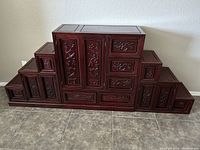 Full front view of all three Japanese step tansu pieces assembled side by side, showing floral carvings and stepped design