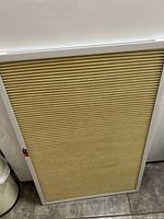 Full view of the rectangular beige pleated mesh air filter with white plastic frame, standing upright.