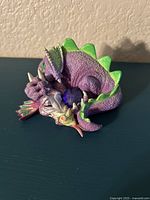 Front angled view of purple dragon figurine with green spikes and large blue crystal on chest, depicting 'Snoozy' from the Mood Dragons collection.