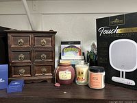 Lot items including wooden jewelry box, scented candles, decorative jars, pens, and boxed LED makeup mirror